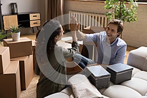 Happy young couple homeowners giving high five enjoy buying house