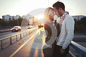 Happy young couple hugging and kissing on bridge