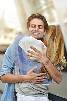 Happy young couple hugging and laughing outdoors.