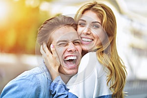 Happy young couple hugging and laughing outdoors.