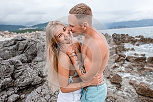 happy young couple hugging and laughing on rocky beach