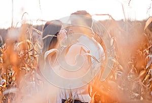 Happy young couple kiss in autumn corn field