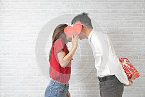 Happy young couple is kissing behind heart on blick wall background