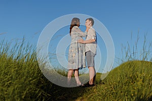 Happy young couple kissing on top of a mountain, with clear sky in the background