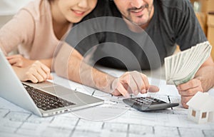 Happy couple holding money and calculating their budget.