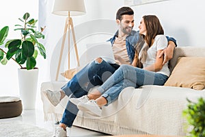 happy young couple with laptop looking at each other on couch