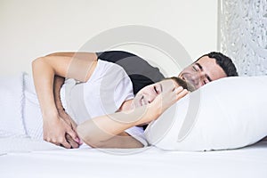 Happy young couple lay down and sleeping or waking up in the early morning at home. white bedroom at home and people hugging with