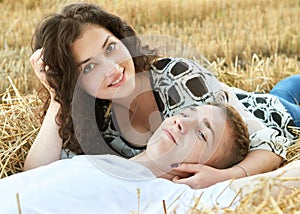 Happy young couple lie in straw, wheaten field at evening, romantic people concept, beautiful landscape, summer season