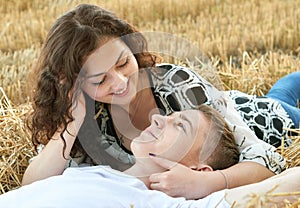 Happy young couple lie in straw, wheaten field at evening, romantic people concept, beautiful landscape, summer season