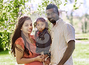 Happy young couple with a little daughter in park