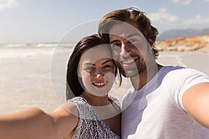 Happy young couple looking at camera on beach