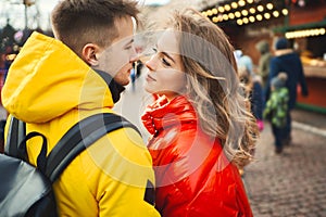 Happy young couple looking at each other with smile, wearning in bright yellow and red down jackets.