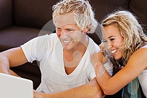 Happy young couple looking at laptop