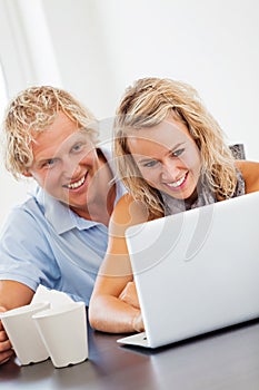 Happy young couple looking at laptop