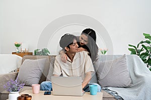 Happy young couple looking laptop relax on sofa in living room watch video on laptop together