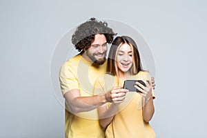 Happy young couple looking at mobile phone isolated on white background