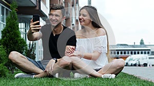 Happy young couple looking at smartphone, have video call, calling friends or relatives, social media