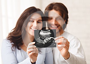 Happy young couple looking at sonography picture of their baby
