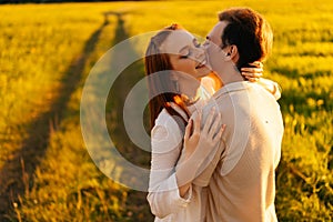 Happy young couple in love with closed eyes hugging, kissing, stroking standing together on green meadow in summer