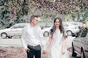 Happy young couple in love enjoys spring day, loving man holding on hands his woman carefree walking at park