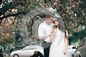 Happy young couple in love enjoys spring day, loving man holding on hands his woman carefree walking at park