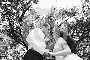 Happy young couple in love enjoys spring day, loving man holding on hands his woman carefree walking at park