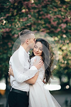 Happy young couple in love enjoys spring day, loving man holding on hands his woman carefree walking at park