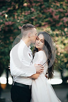 Happy young couple in love enjoys spring day, loving man holding on hands his woman carefree walking at park