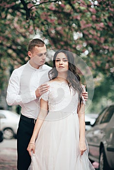 Happy young couple in love enjoys spring day, loving man holding on hands his woman carefree walking at park