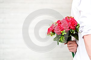Happy young couple in love hugging and holding red roses in the hands for surprise his girlfriend, couple concept, valentine`s da