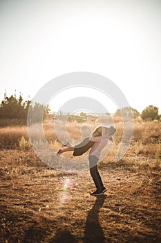 Happy young couple in love, hugging, she is jumping,he is holding her in embrace, enjoying outdoors in a wheat field at sunset