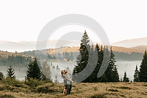 Happy young couple in love hugging and laughing in the mountains outdoors