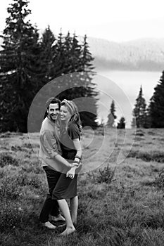 Happy young couple in love hugging and laughing in the mountains outdoors