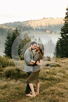 Happy young couple in love hugging and laughing in the mountains outdoors