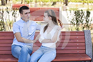 Happy young couple in love sitting on a park bench