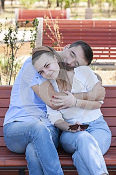 Happy young couple in love sitting on a park bench