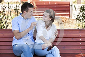 Happy young couple in love sitting on a park bench