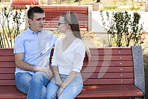 Happy young couple in love sitting on a park bench