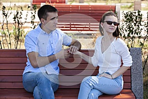 Happy young couple in love sitting on a park bench