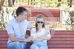 Happy young couple in love sitting on a park bench