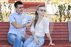 Happy young couple in love sitting on a park bench