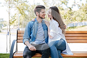 Happy young couple in love sitting on a park bench