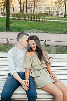 Happy young couple in love sitting on a park bench and hugging