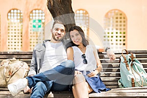 Happy young couple in love sitting on street bench and looking a