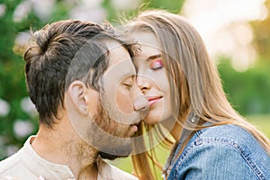 Happy young couple in love smiling and enjoying a walk in the summer Park. Romance and the concept of rest. Girl affectionately ca