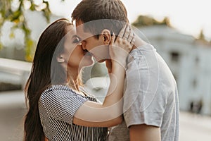 Happy young couple in love teenagers friends dressed in casual style kissing at street