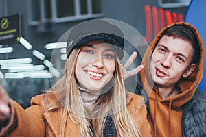 Happy young couple in love teenagers friends dressed in casual style making selfie on city street in cold season