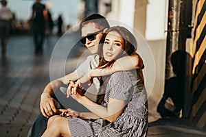 Happy young couple in love teenagers friends dressed in casual style sitting together on city street