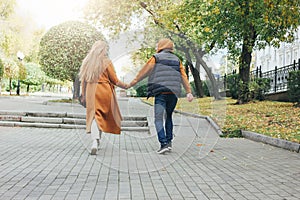 Happy young couple in love teenagers friends dressed in casual style walking together on the autumn city street