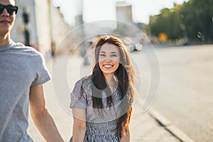 Happy young couple in love teenagers friends dressed in casual style walking together on city street